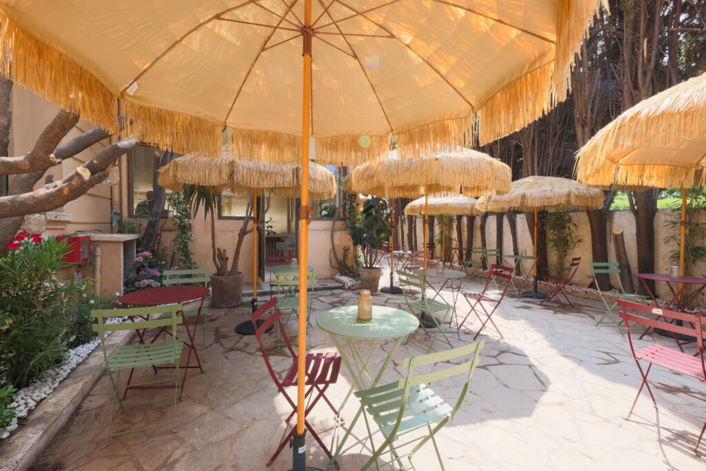 terrasse de l’hôtel avec chaises colorées et parasols en paille